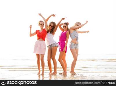 summer vacation, holidays, travel and people concept - group of smiling young women in sunglasses and casual clothes dancing on beach
