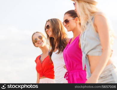 summer vacation, holidays, travel and people concept - group of smiling young women in sunglasses and casual clothes on beach