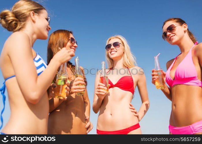 summer vacation, holidays, travel and people concept - group of smiling young women sunbathing and drinking on beach