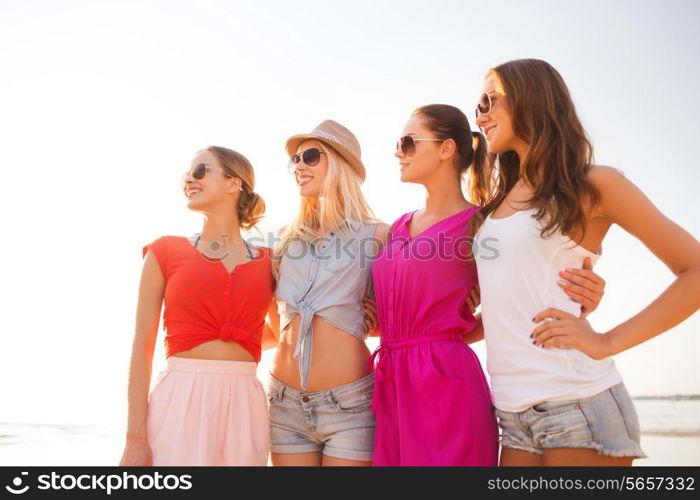 summer vacation, holidays, travel and people concept - group of smiling young women in sunglasses and casual clothes on beach