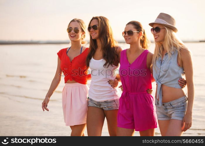 summer vacation, holidays, travel and people concept - group of smiling young women in sunglasses and casual clothes on beach