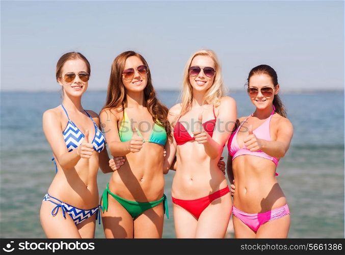 summer vacation, holidays, travel and people concept - group of smiling young women showing thumbs up on beach