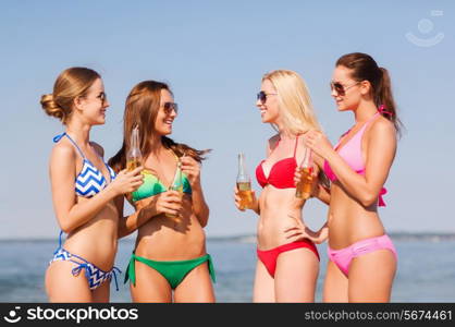 summer vacation, holidays, travel and people concept - group of smiling young women sunbathing and drinking on beach