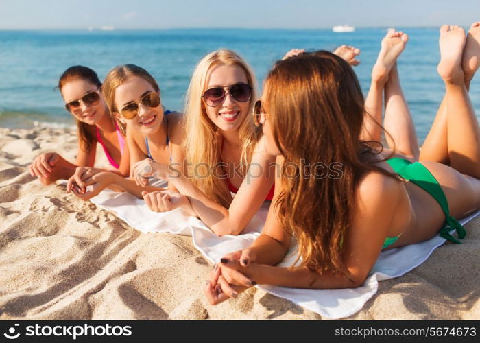 summer vacation, holidays, travel and people concept - group of smiling young women in sunglasses lying on beach