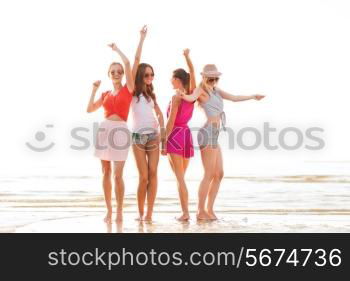 summer vacation, holidays, travel and people concept - group of smiling young women in sunglasses and casual clothes dancing on beach