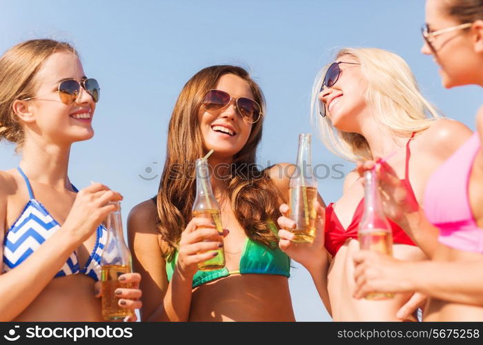 summer vacation, holidays, travel and people concept - group of smiling young women sunbathing and drinking on beach