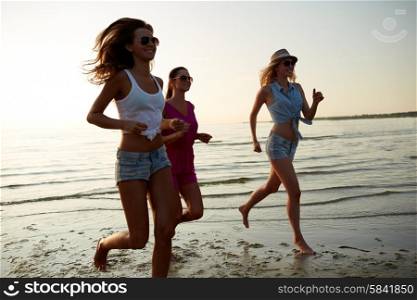 summer vacation, holidays, travel and people concept - group of smiling young women in sunglasses and casual clothes running on beach