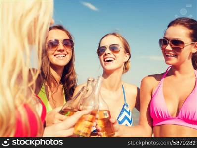 summer vacation, holidays, travel and people concept - group of smiling young women sunbathing and drinking on beach