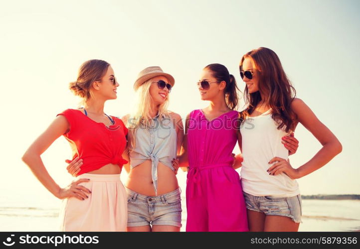 summer vacation, holidays, travel and people concept - group of smiling young women in sunglasses and casual clothes on beach