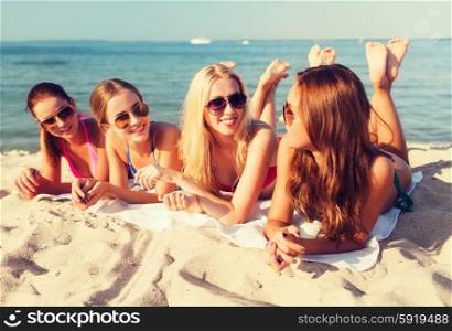 summer vacation, holidays, travel and people concept - group of smiling young women in sunglasses lying on beach