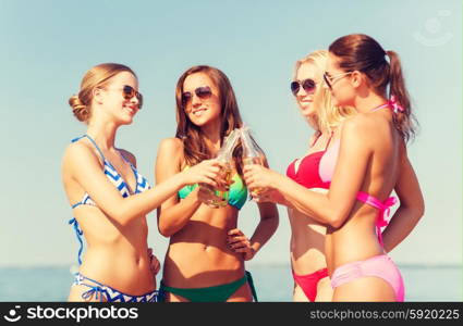 summer vacation, holidays, travel and people concept - group of smiling young women sunbathing and drinking on beach