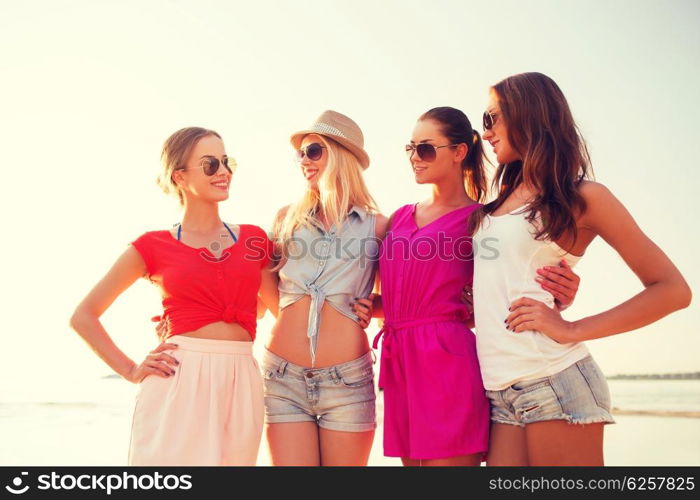 summer vacation, holidays, travel and people concept - group of smiling young women in sunglasses and casual clothes on beach