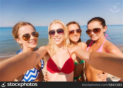 summer vacation, holidays, travel and people concept - group of young smiling women photographing by camera or smartphone on beach