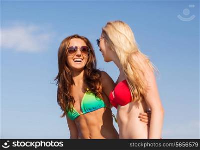 summer vacation, holidays, travel, friendship and people concept - two laughing young women on beach