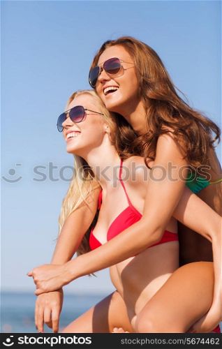 summer vacation, holidays, travel, friendship and people concept - two smiling young women on beach