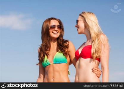 summer vacation, holidays, travel, friendship and people concept - two smiling young women on beach