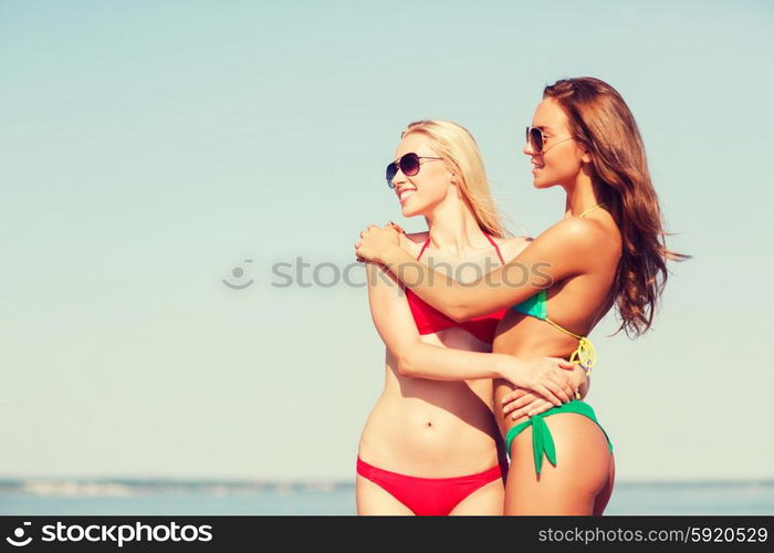 summer vacation, holidays, travel, friendship and people concept - two smiling young women on beach