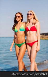 summer vacation, holidays, travel, friendship and people concept - two smiling young women walking on beach