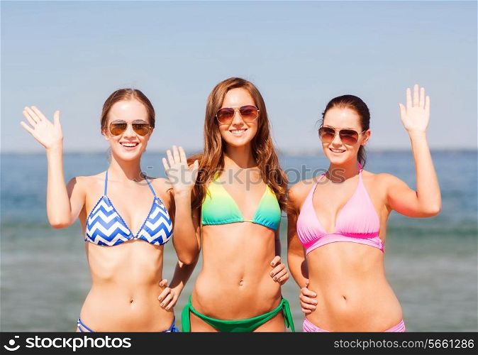 summer vacation, holidays, travel, gesture and people concept - group of smiling young women waving hands on beach
