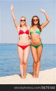 summer vacation, holidays, travel, gesture and people concept - two smiling young women waving hands on beach