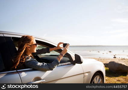 summer vacation, holidays, travel, road trip and people concept - happy smiling teenage girl or young woman in car at seaside