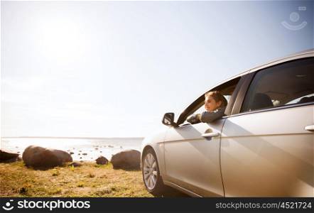 summer vacation, holidays, travel, road trip and people concept - happy smiling teenage girl or young woman in car at seaside
