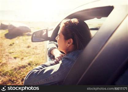 summer vacation, holidays, travel, road trip and people concept - happy smiling teenage girl or young woman in car at seaside. happy teenage girl or young woman in car
