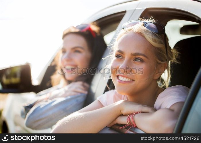 summer vacation, holidays, travel, road trip and people concept - happy teenage girls or young women in car at seaside
