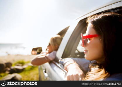 summer vacation, holidays, travel, road trip and people concept - happy teenage girls or young women in car at seaside