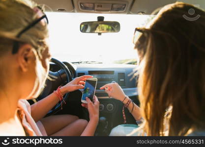 summer vacation, holidays, travel, road trip and people concept - happy teenage girls or young women with smartphone taking selfie in car