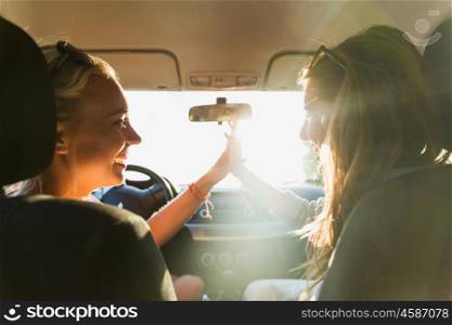 summer vacation, holidays, travel, road trip and people concept - happy teenage girls or young women driving in car and making high five gesture