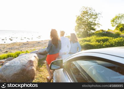 summer vacation, holidays, travel, road trip and people concept - happy teenage girls or young women near car at seaside