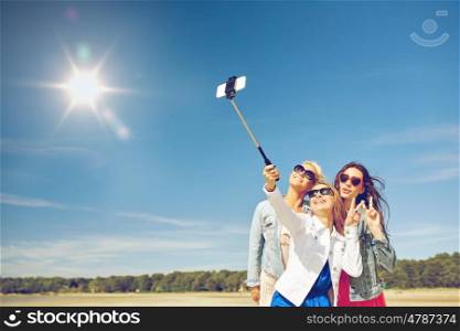 summer vacation, holidays, travel, technology and people concept- group of smiling young women taking picture with smartphone on selfie stick on beach