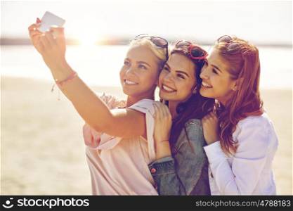 summer vacation, holidays, travel, technology and people concept- group of smiling young women taking selfie with smartphone on beach