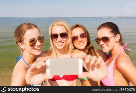 summer vacation, holidays, travel, technology and people concept- group of smiling young women on beach making selfie with smartphone over blue sky background