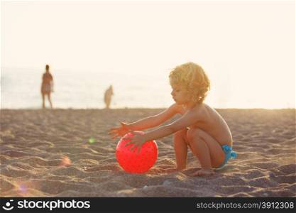 Summer vacation - little girl playing on sandy beach at sunset