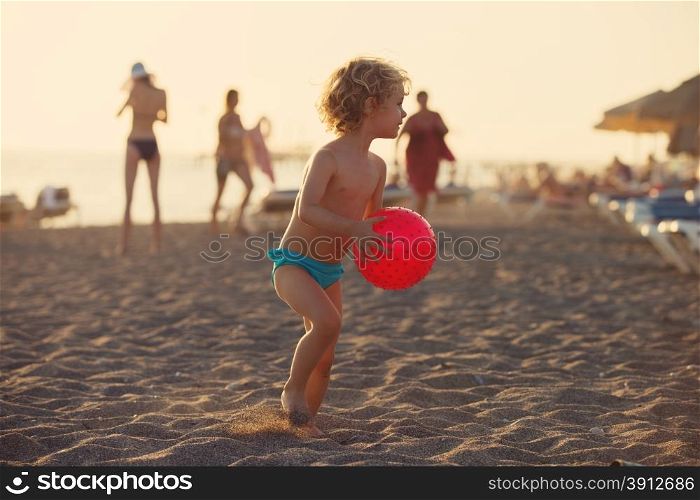 Summer vacation - little girl playing on sandy beach at sunset