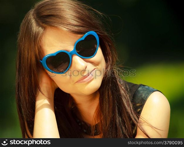 Summer vacation. Portrait of attractive brunette beautiful young woman in blue sunglasses in the shape of heart outdoor.