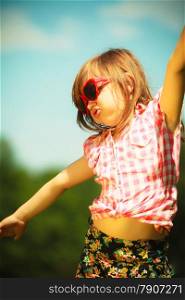 Summer vacation. Portrait of cute little girl kid child in red sunglasses in the shape of heart playing in flying outdoor.