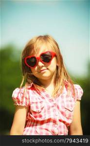 Summer vacation. Portrait of cute little girl kid child in red sunglasses in the shape of heart outdoor.
