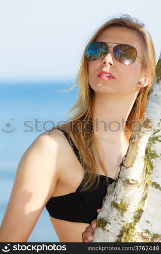 Summer vacation. Sexy girl in bikini standing on the beach. Young woman relaxing on the sea coast. Summertime.