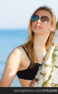 Summer vacation. Sexy girl in bikini standing on the beach. Young woman relaxing on the sea coast. Summertime.