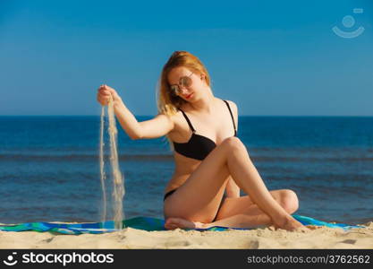 Summer vacation. Sexy girl in bikini sunbathing tanning on the beach. Young woman relaxing on the sea coast. Summertime.