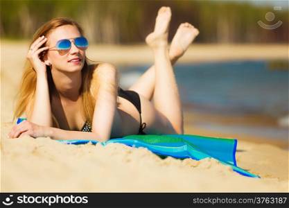 Summer vacation. Sexy girl in bikini sunbathing tanning on the beach. Young woman relaxing on the sea coast. Summertime.