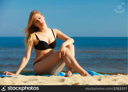 Summer vacation. Sexy girl in bikini sunbathing tanning on the beach. Young woman relaxing on the sea coast. Summertime.