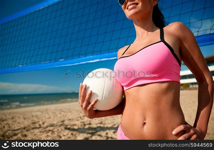 summer vacation, sport and people concept - close up of young woman with volleyball ball and net on beach