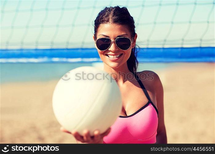 summer vacation, sport and people concept - young woman with volleyball ball and net on beach