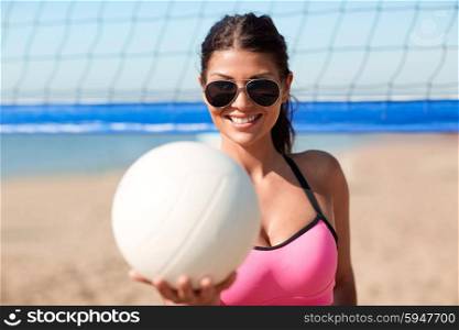 summer vacation, sport and people concept - young woman with volleyball ball and net on beach