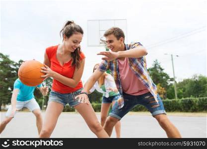summer vacation, sport, games and friendship concept - group of happy teenagers playing basketball outdoors