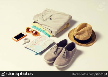 summer vacation, tourism and objects concept - close up of clothes, smartphone, personal stuff and travel map
